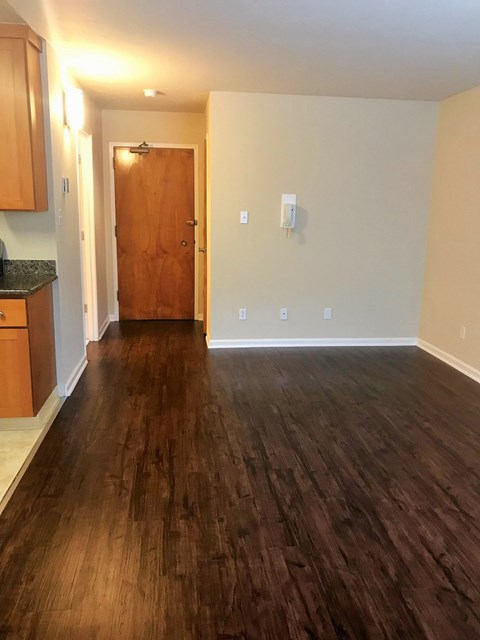 a living room with wood flooring and a door into a kitchen